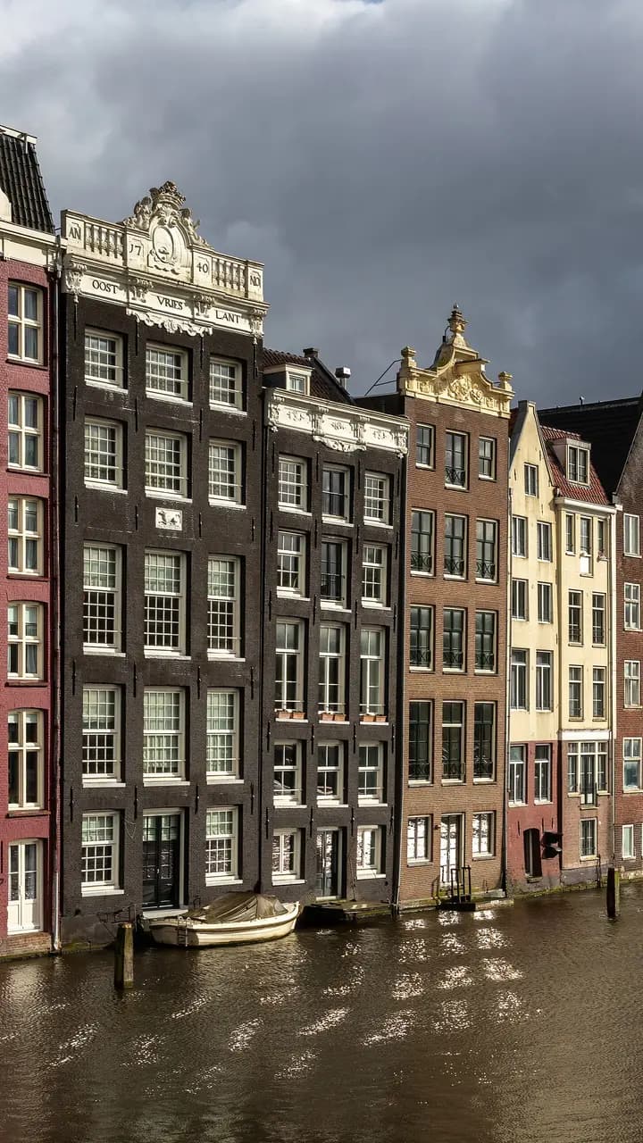 Colorful canal houses at golden hour in Damrak avenue Amsterdam the Netherlands